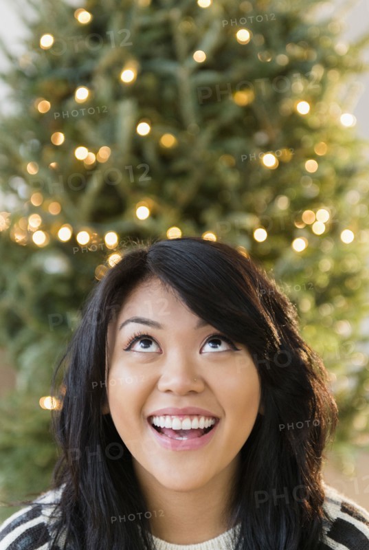 Pacific Islander woman looking up near Christmas tree