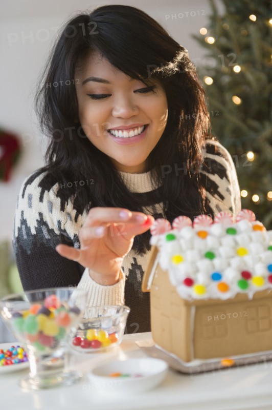 Pacific Islander woman decorating gingerbread house