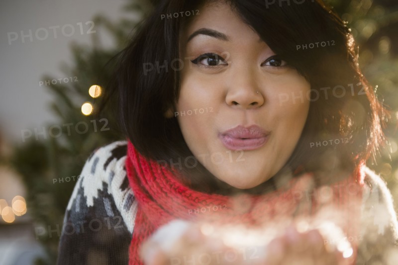 Pacific Islander woman blowing snow at Christmas