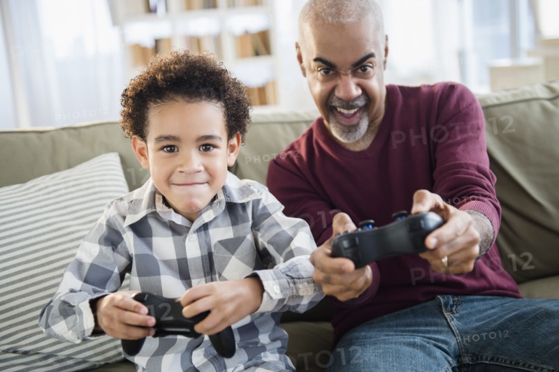 Mixed race grandfather and grandson playing video games