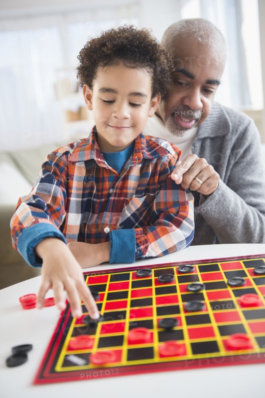 Mixed race grandfather and grandson playing checkers