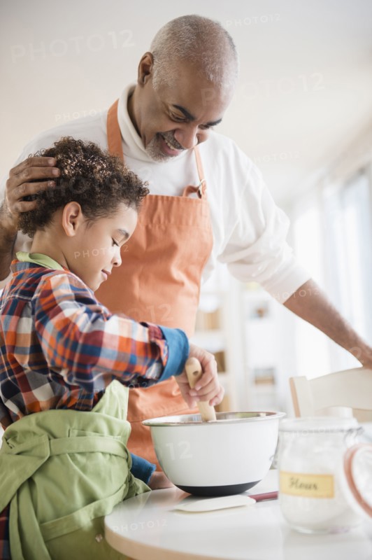 Mixed race grandfather and grandson baking in kitchen