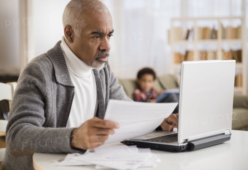 Mixed race man paying bills on laptop