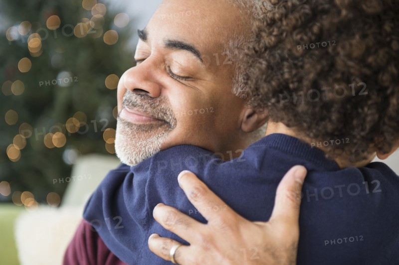 Mixed race grandfather and grandson hugging at Christmas