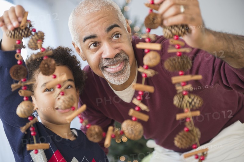 Mixed race grandfather and grandson holding Christmas decorations