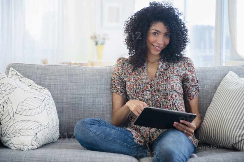 Mixed race woman using digital tablet on sofa