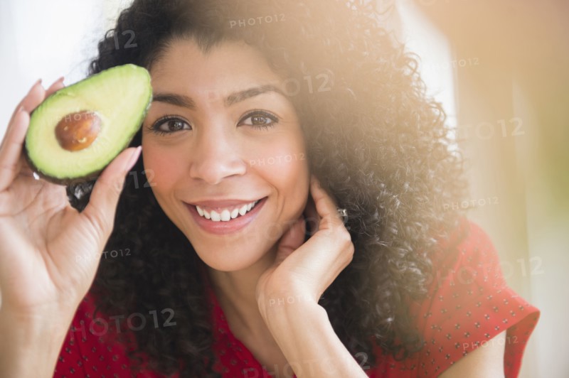 Mixed race woman holding avocado half