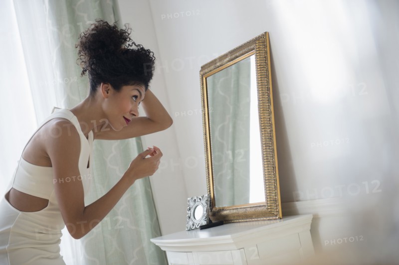 Mixed race woman styling hair in mirror