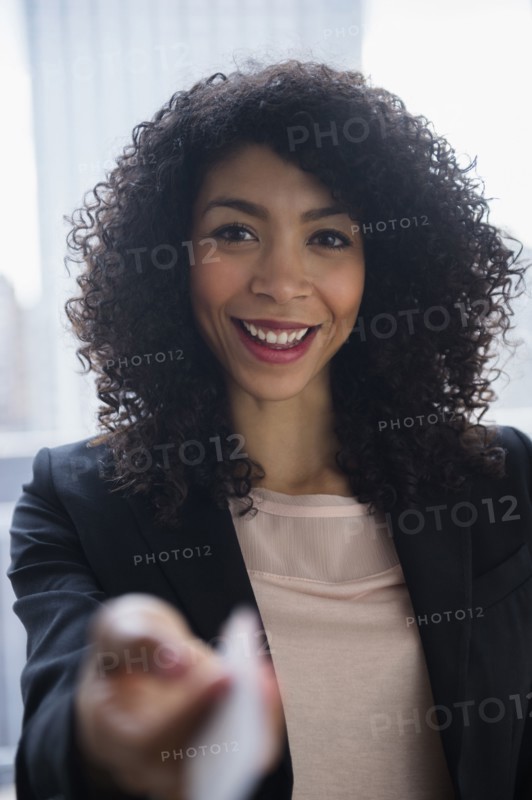 Mixed race businesswoman offering business card in office