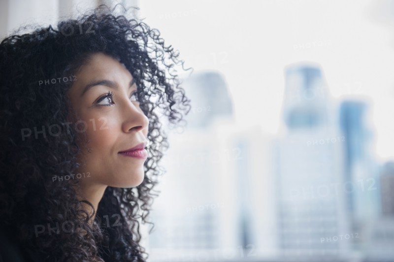 Mixed race businesswoman looking out window