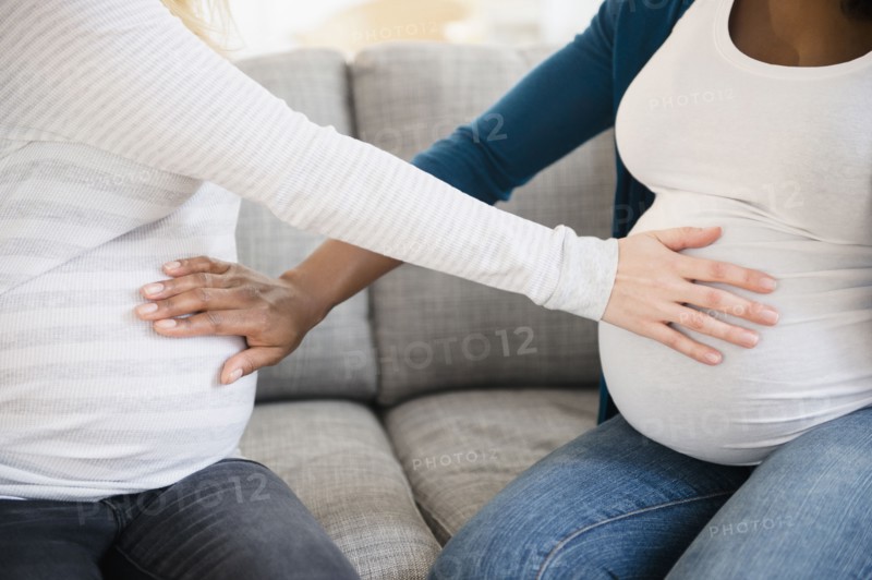 Pregnant women feeling stomachs of each other