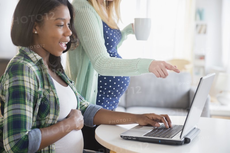 Pregnant women using laptop at table