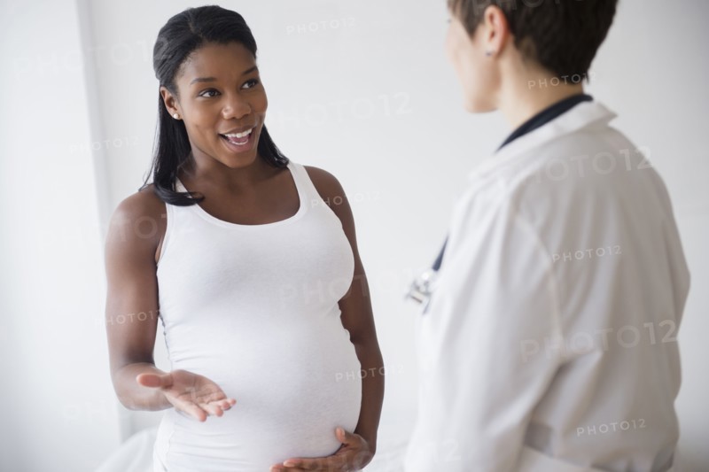 Black pregnant woman talking to doctor