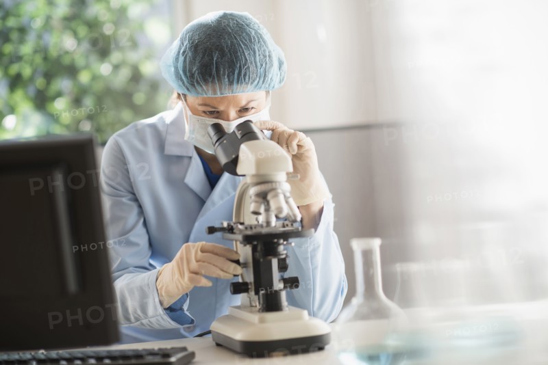Mixed race scientist using microscope in laboratory