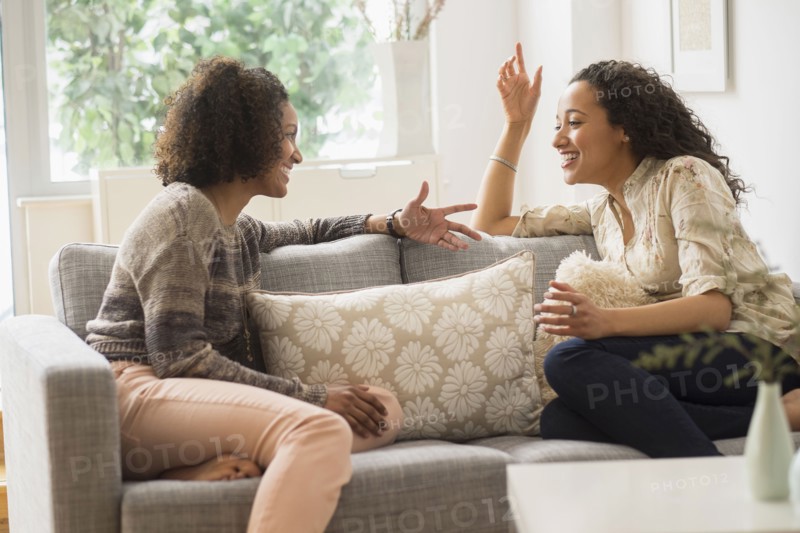 Laughing women talking on sofa