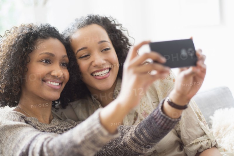 Smiling women taking cell phone photograph