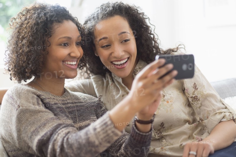 Smiling women taking cell phone photograph