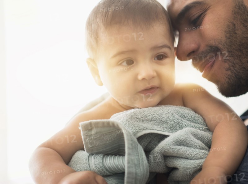 Father drying baby son with towel after bath