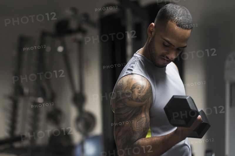 Close up of Hispanic man lifting weights in gym