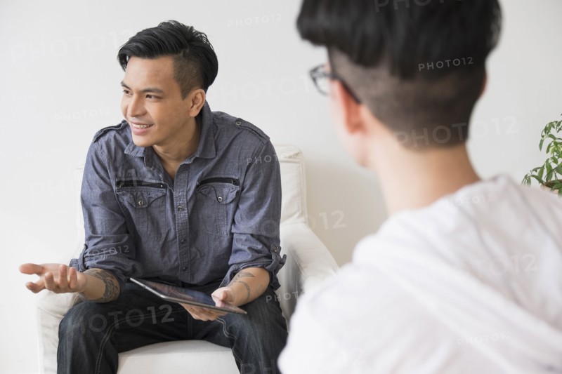 Men using digital tablet in living room