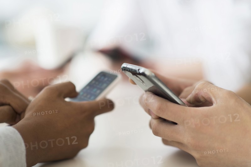 Close up of friends texting with cell phones at table