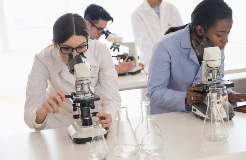 Scientists using microscopes in research laboratory