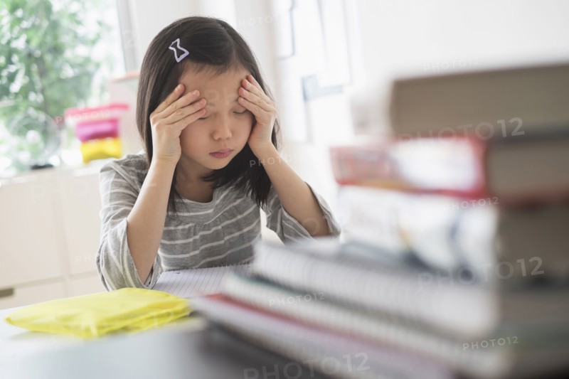 Anxious Chinese student rubbing forehead doing homework