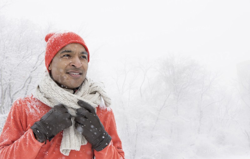 Black man wearing gloves and scarf in snow