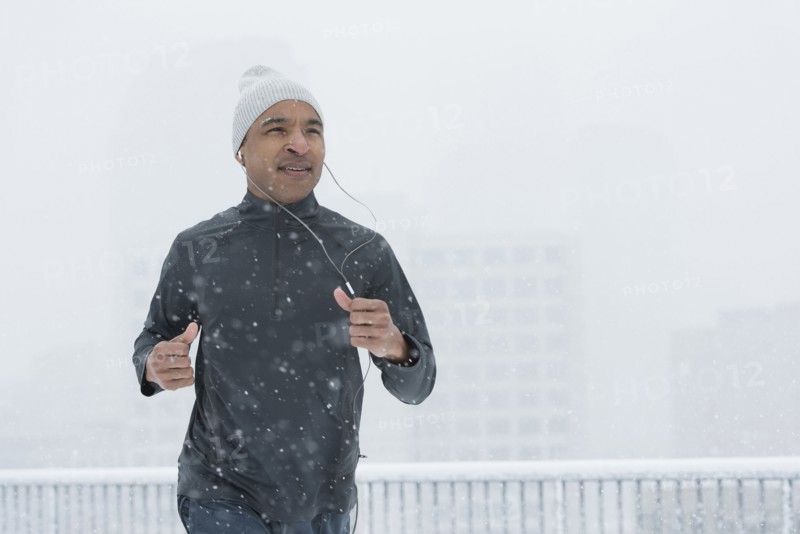 Black runner jogging in snow