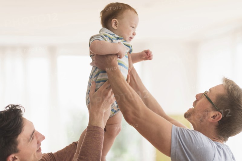 Caucasian gay fathers holding baby