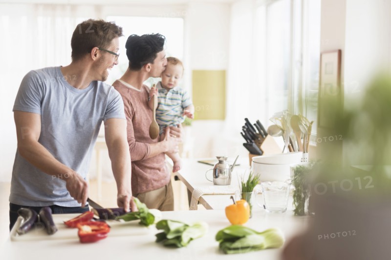 Caucasian gay fathers and baby cooking in kitchen