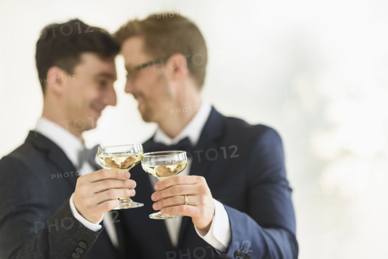 Caucasian gay grooms toasting with champagne at wedding