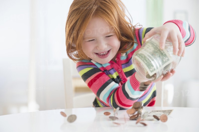Caucasian girl pouring money from change jar
