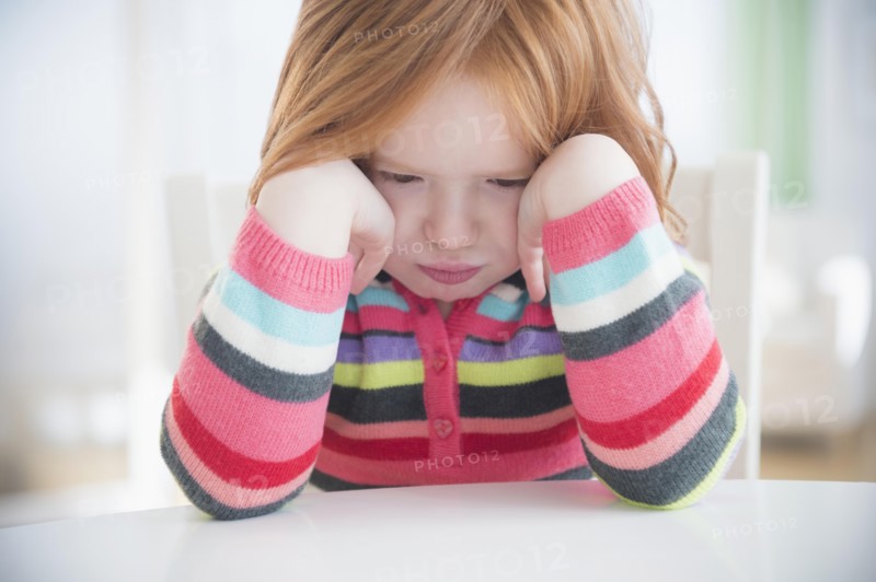 Caucasian girl crying at table