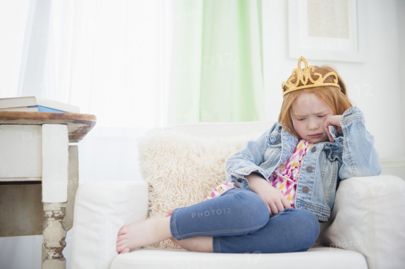 Upset Caucasian girl pouting in armchair