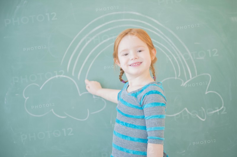 Caucasian girl drawing on chalkboard