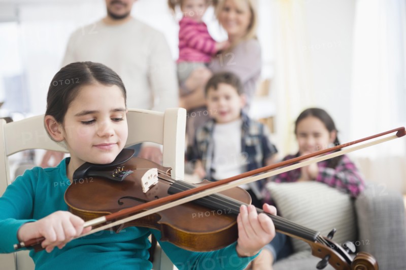 Caucasian girl playing violin in living room
