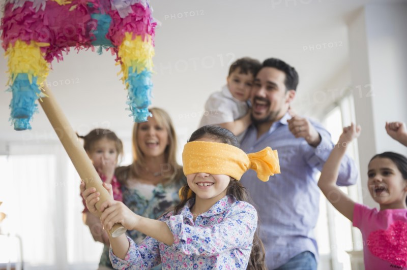 Caucasian girl hitting pinata at birthday party