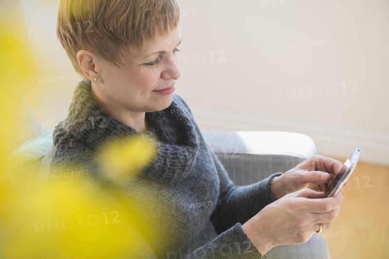 Caucasian woman using cell phone on sofa