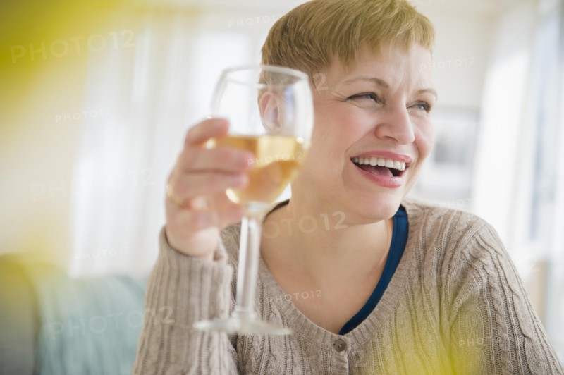 Caucasian woman drinking glass of wine in living room