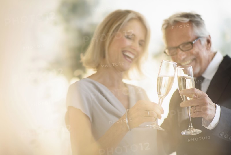 Smiling older Caucasian couple toasting with champagne