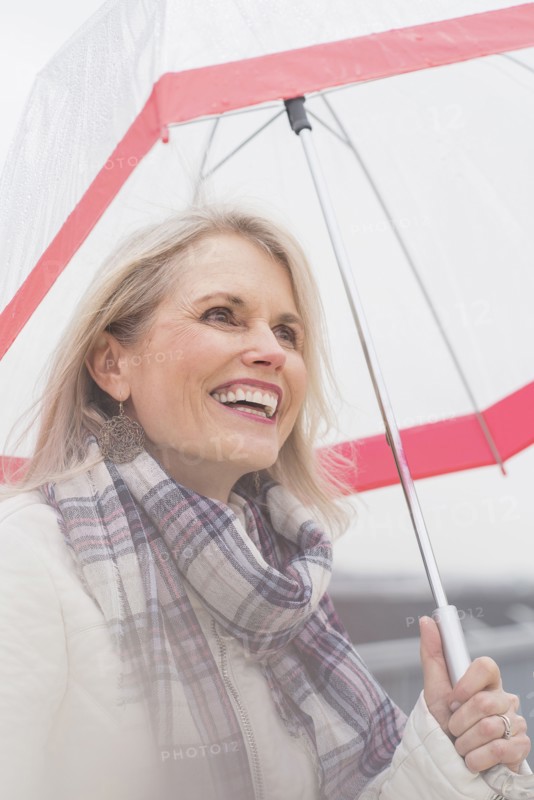 Older Caucasian woman standing under umbrella
