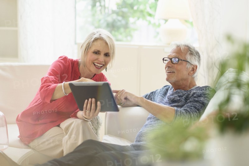 Older Caucasian couple using digital tablet in living room