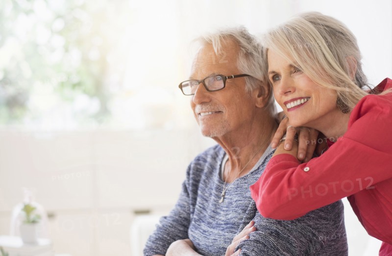 Older Caucasian couple hugging in living room
