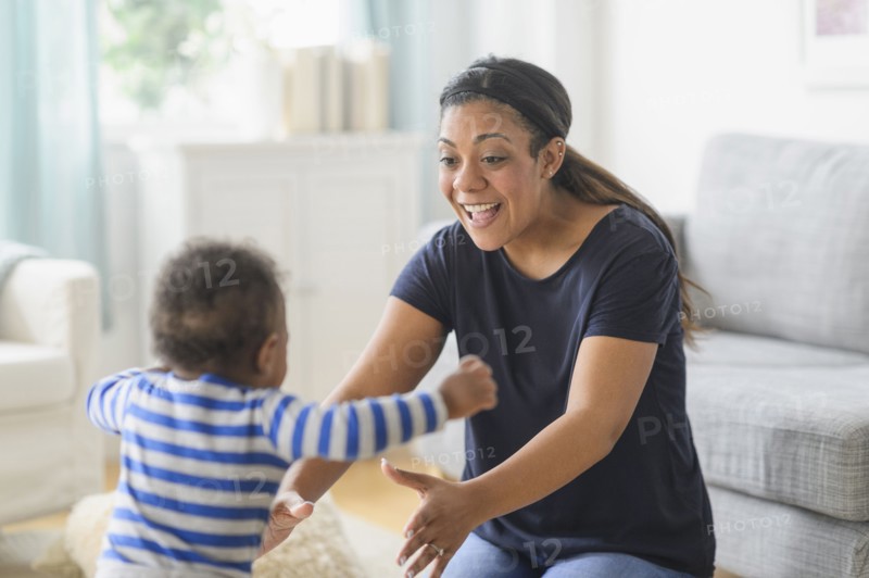 Mixed race mother playing with baby son in living room