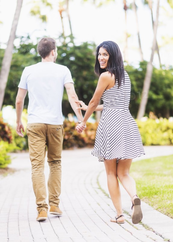 Smiling Hispanic couple walking in park