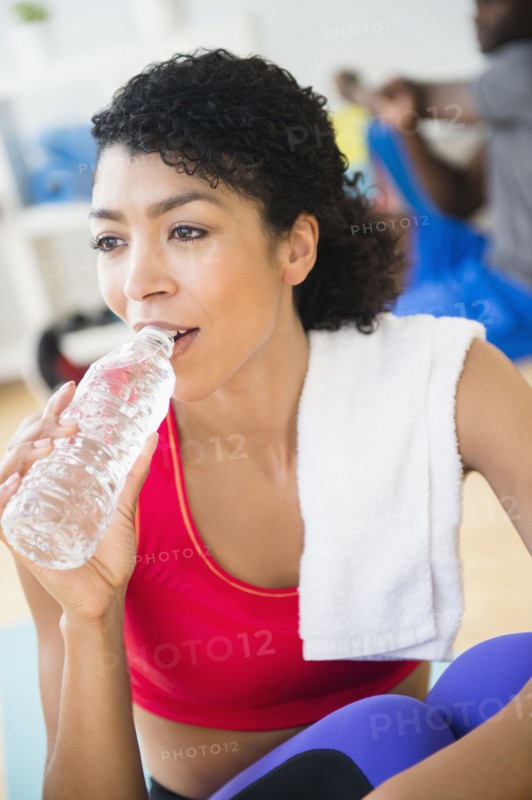 Close up of woman drinking water bottle in gym