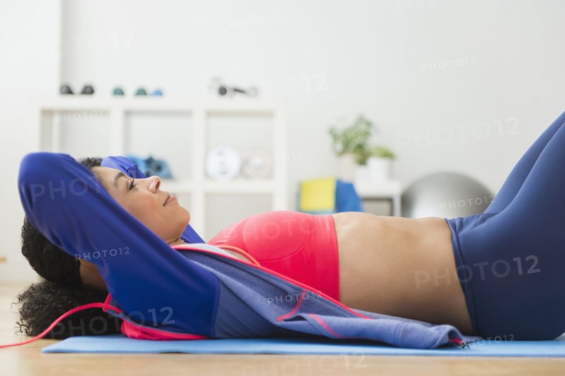 Mixed race woman doing sit-ups in gym