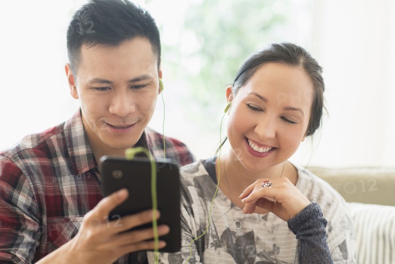 Laughing couple watching digital tablet on sofa