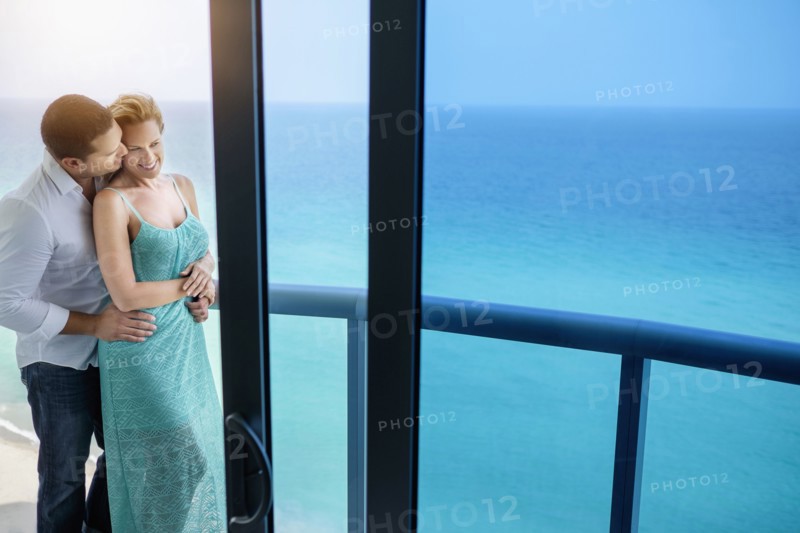 Couple kissing on balcony over ocean